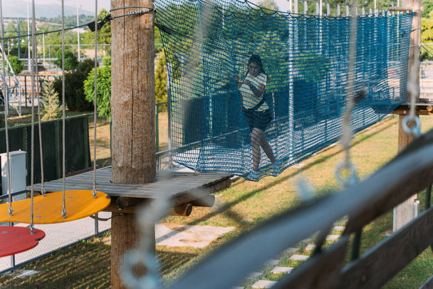 Девочка-подросток изо всех сил пытается закончить веревочный мост. - Фото, изображение