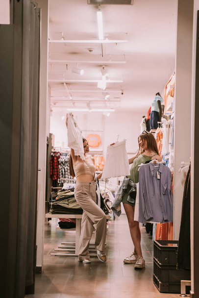 Дві дівчини-підлітки показують свій одяг кожному в магазині
 - Фото, зображення