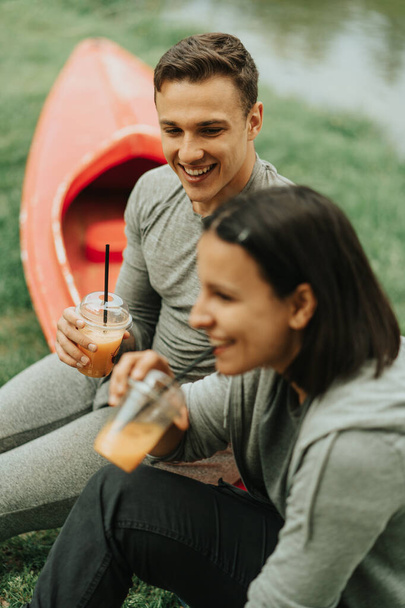 Bella coppia sorridente mentre seduto su un kayak rosso nel parco - Foto, immagini