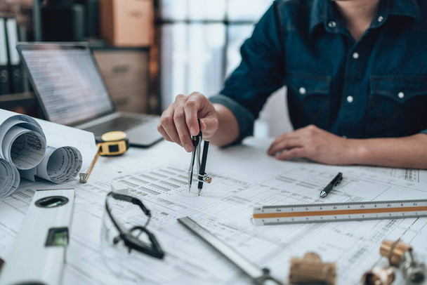 Engineering working with drawings inspection and writing on the office desk and Calculator, triangle ruler, safety glasses, compass, vernier caliper on Blueprint. Engineer, Architect, Industry and factory concept. - Foto, Imagem