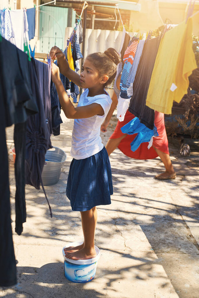 She can do it all by herself. a young girl hanging laundry outside - Foto, Imagem