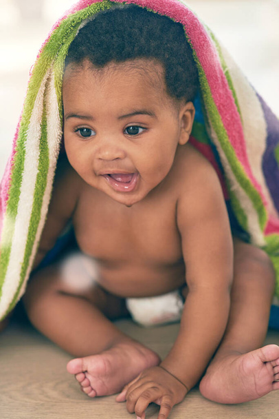 Sweet bundle of joy. an adorable baby girl covered in a colorful blanket at home - Foto, afbeelding