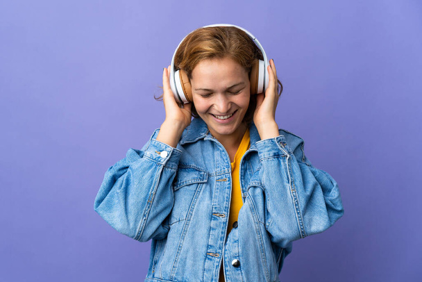fiatal grúz nő elszigetelt lila háttér hallgat zenét - Fotó, kép