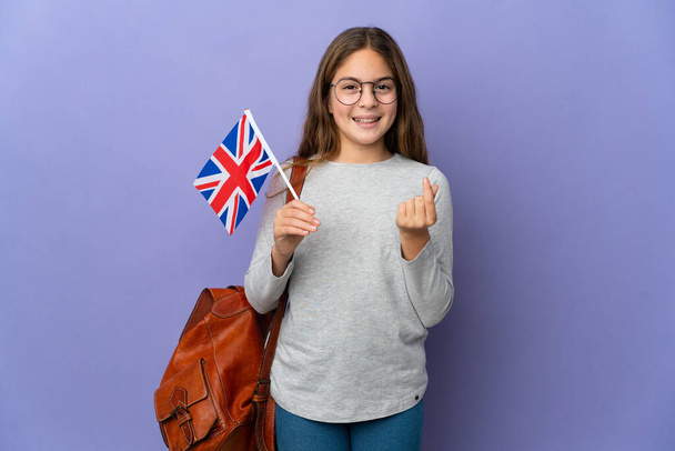 İzole edilmiş arka planda Birleşik Krallık bayrağı taşıyan çocuk para hareketi yapıyor - Fotoğraf, Görsel