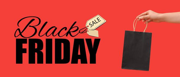Female hand holding shopping bag and text BLACK FRIDAY SALE on red background - Fotó, kép
