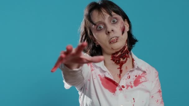Sinister creepy dead woman with deep and bloody wounds on neck prowling at camera. Frightening evil brain-eating monster smirking and growling at camera while covered in blood and flesh. - Video, Çekim