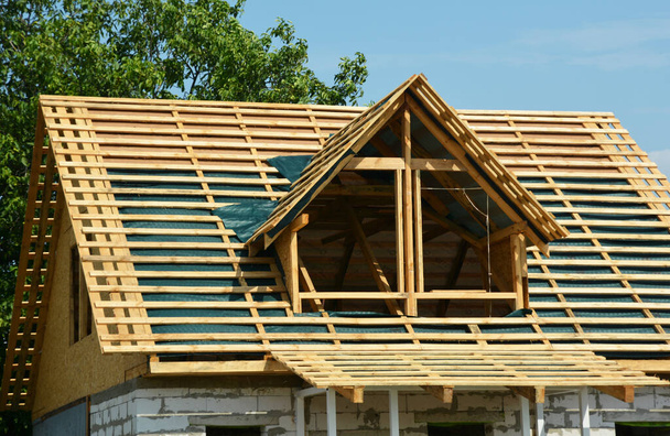 Κατασκευή στέγης με στεγανοποίηση με υγρασία. Εγκατάσταση μιας νέας οροφής φράγματος ατμού και σανίδων ξυλείας σε οροφή πλαισίου με παράθυρο οροφής mansard πριν από την εγκατάσταση πλακιδίων. - Φωτογραφία, εικόνα