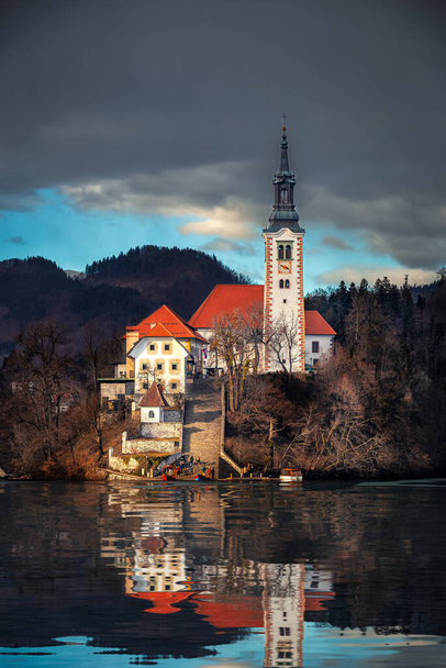 Lake Bled, Slovenia - Beautiful view of Lake Bled (Blejsko Jezero) with reflecting Pilgrimage Church of the Assumption of Maria on Bled Island with dark clouds at winter time - Foto, Bild