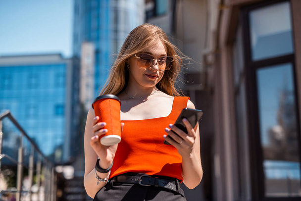 Portrait of a confident woman in elegant casual clothes and using a smartphone on a city street. Manager in a big city. Communication with people on the Internet. - Foto, Bild