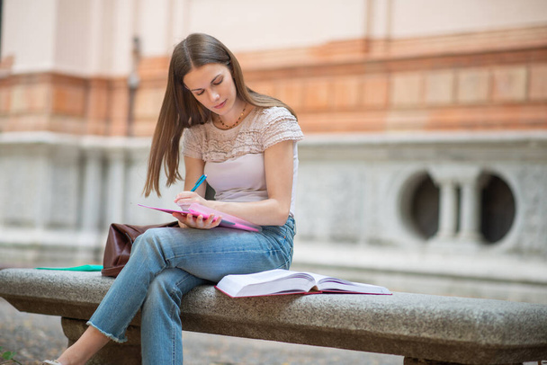 Portrait of a female student studying in a park in front of the school - Photo, Image