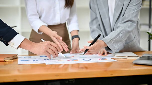 A young financial consultant group is working, brainstorming and analysing the financial data together in the office. cropped image - 写真・画像