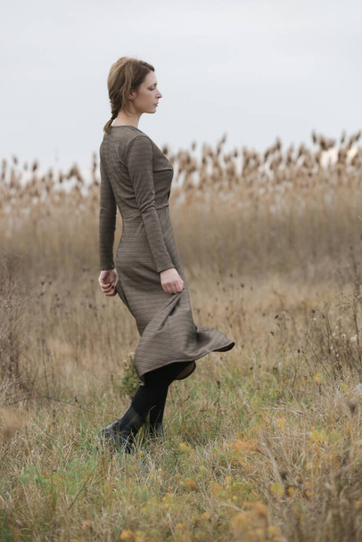 Fashion outdoor portrait of young woman in autumn brown long sleeve dress. - Foto, imagen