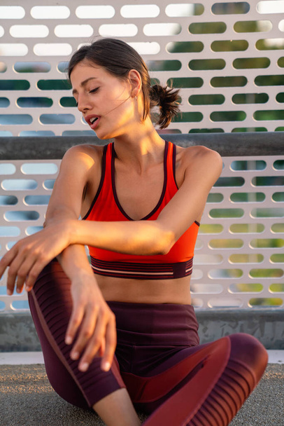 Portrait of tired fitness young woman takeing a break during workout in the city. People sport concept - 写真・画像
