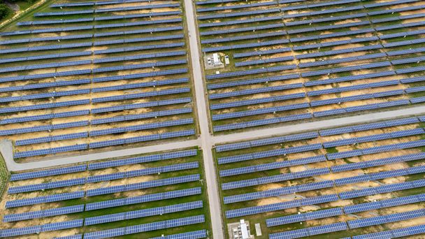 Aerial view of solar power plant on green field. Solar panels system for solar power generation. Green energy for sustainable development to prevent climate change and global warming to protect earth. - 写真・画像