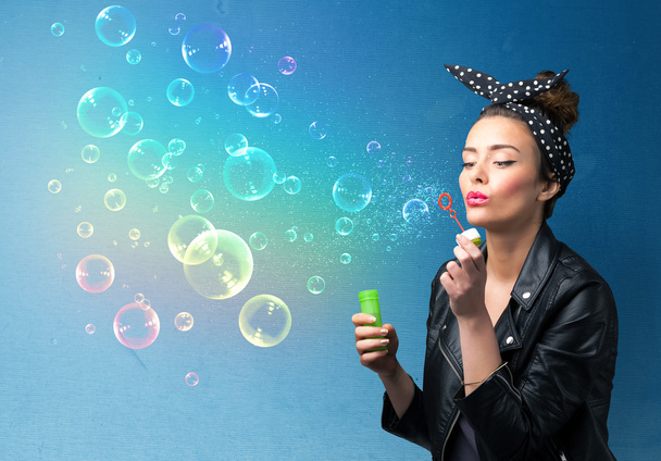 Pretty lady blowing colorful bubbles on blue background - Foto, Imagem
