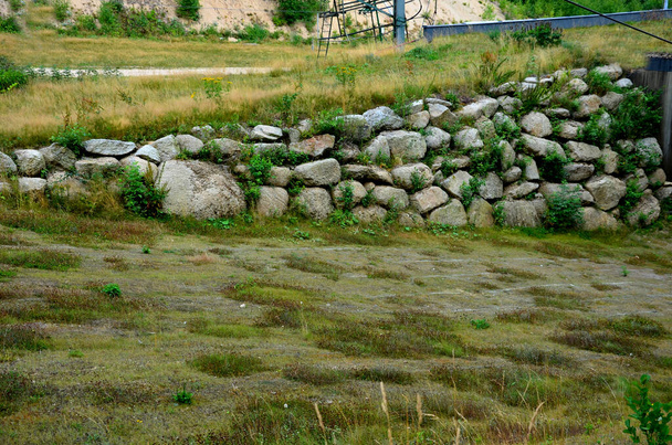 landscaping in the countryside using an excavator. Retaining walls made of massive large boulders dry-stacked into the slope. around cuts of highways, roads and train lines - Photo, Image
