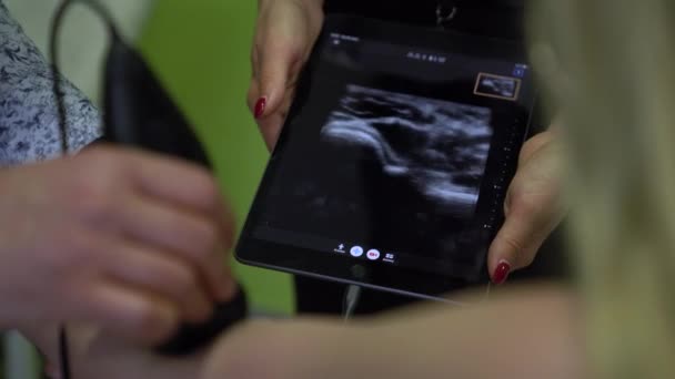 Doctor makes an ultrasound examination with a portable scanner to the patient diagnosing. Sinography displayed on a tablet at the doctor - Imágenes, Vídeo