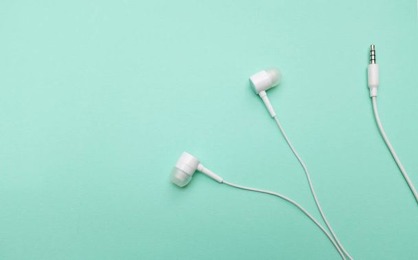 white music headphones ,earphones with headset on isolated bright green pastel background. Music concept. Top view - Photo, image