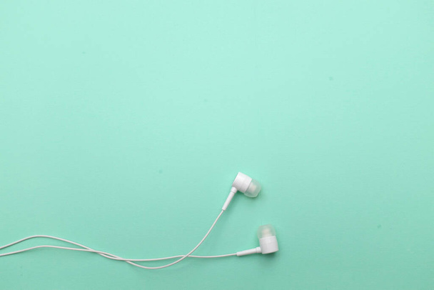 white music headphones ,earphones with headset on isolated bright green pastel background. Music concept. copy space - Valokuva, kuva