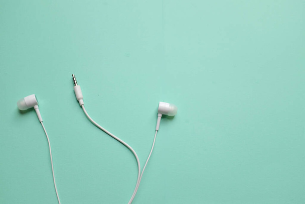 white music headphones ,earphones with headset on isolated bright green pastel background. Music concept. Top view - Φωτογραφία, εικόνα