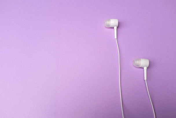 white music headphones ,earphones with headset on isolated bright purple pastel background. Music concept. Top view - Φωτογραφία, εικόνα