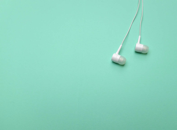 white music headphones ,earphones with headset on isolated bright green pastel background. Music concept.  - Foto, Imagen