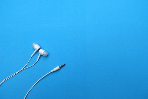 white music headphones ,earphones with headset on isolated bright blue background. Music concept. copy space - Fotó, kép