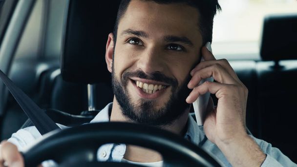 молодий і щасливий чоловік водить машину під час дзвінка на мобільний телефон
 - Фото, зображення