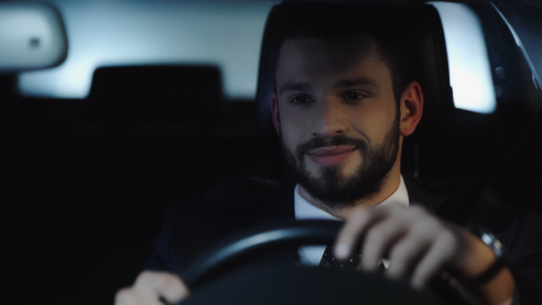 smiling bearded businessman driving car in evening - 写真・画像