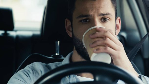 young man driving car and drinking coffee from paper cup - Photo, Image