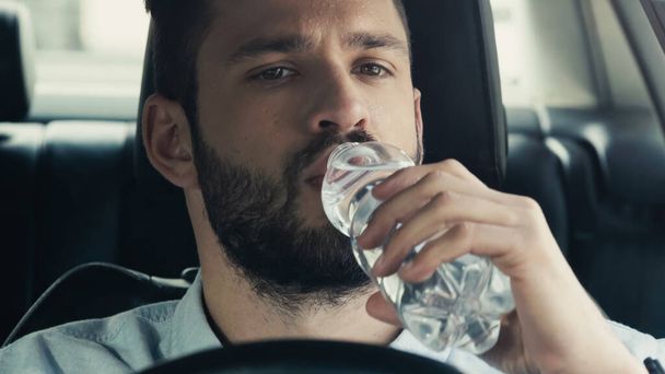 young man driving car and drinking fresh water from plastic bottle - Photo, Image
