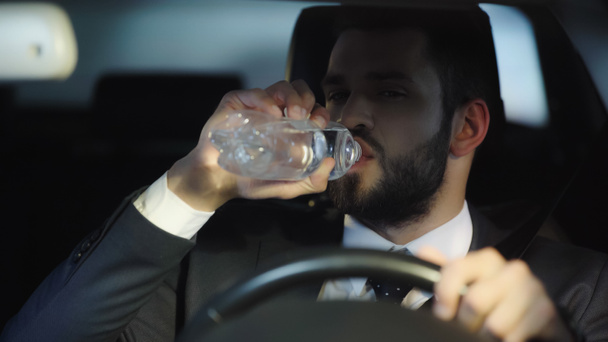 thirsty businessman driving car and drinking pure water from plastic bottle - Foto, immagini