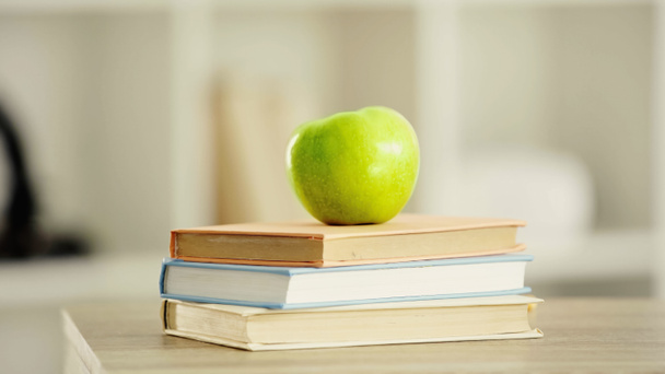 зелене і свіже яблуко на стосі книг на дерев'яному столі
 - Фото, зображення