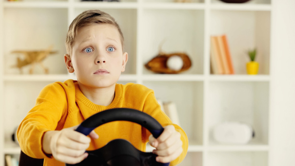 sad schoolboy holding toy steering wheel and playing video game - Foto, Imagem