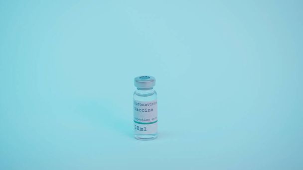 glass bottle with coronavirus vaccine and injection only lettering on blue  - Foto, afbeelding