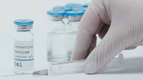 cropped view of person taking syringe near bottles with vaccine isolated on white  - Valokuva, kuva