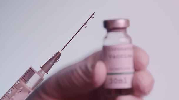 cropped view of scientist holding syringe and blurred bottle with vaccine isolated on grey  - Foto, afbeelding
