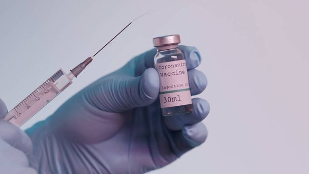 cropped view of scientist in latex gloves holding syringe and bottle with vaccine isolated on grey  - Foto, afbeelding