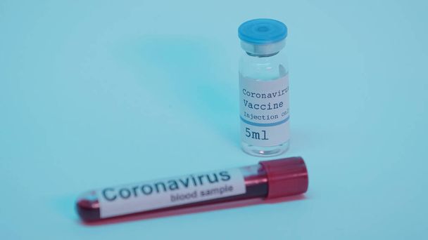 sample with blood in test tube and bottle with coronavirus vaccine on blue - 写真・画像
