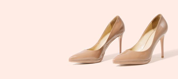 Closeup beige women patent leather shoes isolated on pink background. Stilettos shoe type. Summer fashion and shopping concept. Luxury, glamour party ladies wardrobe accessory. Selective focus. Banner - Photo, image