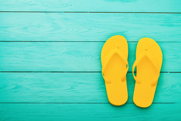 Yellow flip flops on blue wooden background. Summer holidays. Top view. Mock up. Copy space - Фото, изображение