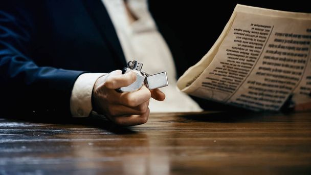 Cropped view of businessman holding lighter and newspaper isolated on black  - Foto, Imagen