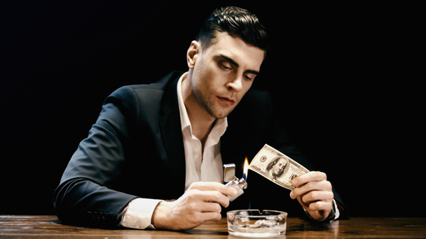 Businessman burning dollar banknote near ashtray isolated on black  - Foto, Imagem