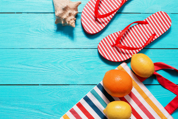 Sommerspaß und Früchte auf blauem Holzgrund. Mock up und malerisch. Orange, Zitronenfrüchte im Beutel und Flip Flops auf dem Boden. Ansicht von oben und Kopierraum - Foto, Bild