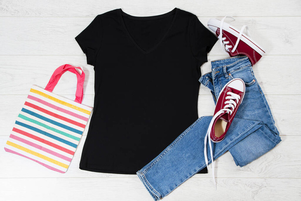 T shirt black and sneakers. T-shirt Mockup flat lay with summer accessories. Jeans and sneakers on wooden floor background. Copy space. Template blank canvas. Front top view. - Photo, Image