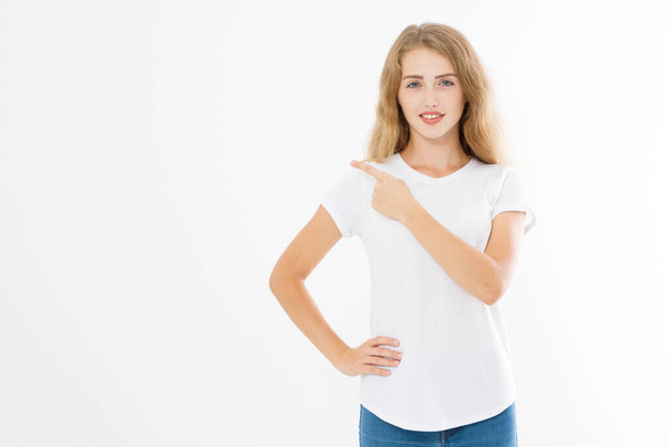 Портрет улыбающейся молодой белокурой белокурой женщины в летней футболке, указывающей пальцем на копировальное пространство, выделенный на белом шаблоне и пустом фоне. Шок и возбужденное лицо. - Фото, изображение