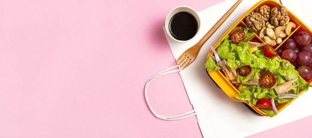 Healthy Food in Plastic container ready to eat with homemade lettuce salad with tomato, onion, corn, tuna, roga grapes, walnuts and cashews in paper bag fro, above. Take away concept - 写真・画像