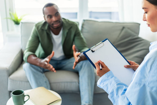 Psychological assistance. African american man having counseling session with therapist at office. Desperate young guy with emotional problem receiving help from psychiatrist at clinic - Foto, Imagen