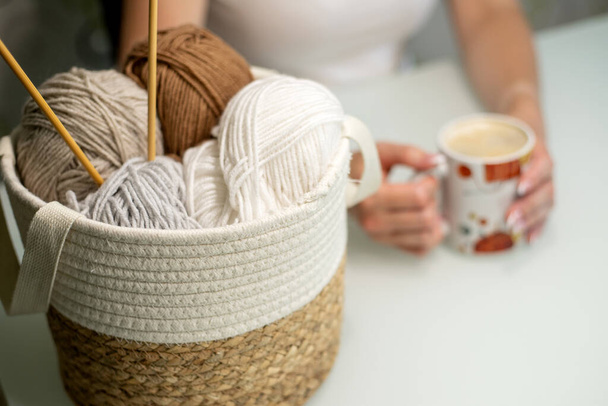 Womens hobby knitting. Pastel colored yarn in basket on white table. - Fotó, kép