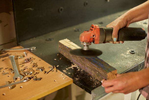 Close up of a worker woman hand grinds, sanding the wood in workshop, restoring antique - Foto, imagen